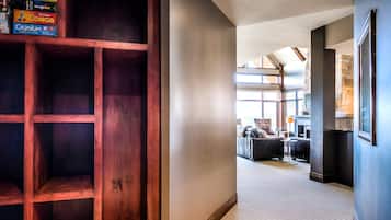 Un pasillo con una estantería de madera, una sala de estar moderna con sofás y una pared de acento de piedra.
