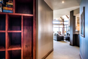 Ein Flur mit einem Holzregal, ein modernes Wohnzimmer mit Sofas und einer Wand aus Stein.