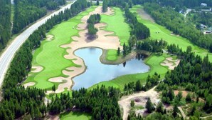 An aerial view of a golf course with a large pond, surrounded by dense forests and a road running parallel to the course. - Altitude - Tremblant Luxurious Ski-in Ski-out Condo - Breathtaking Views (Mont-Tremblant)
