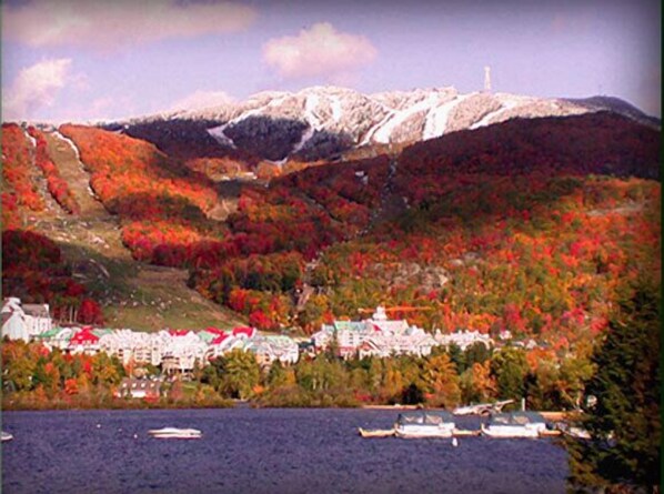 A coastal town with buildings along a waterfront, a mountain in the background, and boats in the water. - Altitude - Tremblant Luxurious Ski-in Ski-out Condo - Breathtaking Views (Mont-Tremblant)
