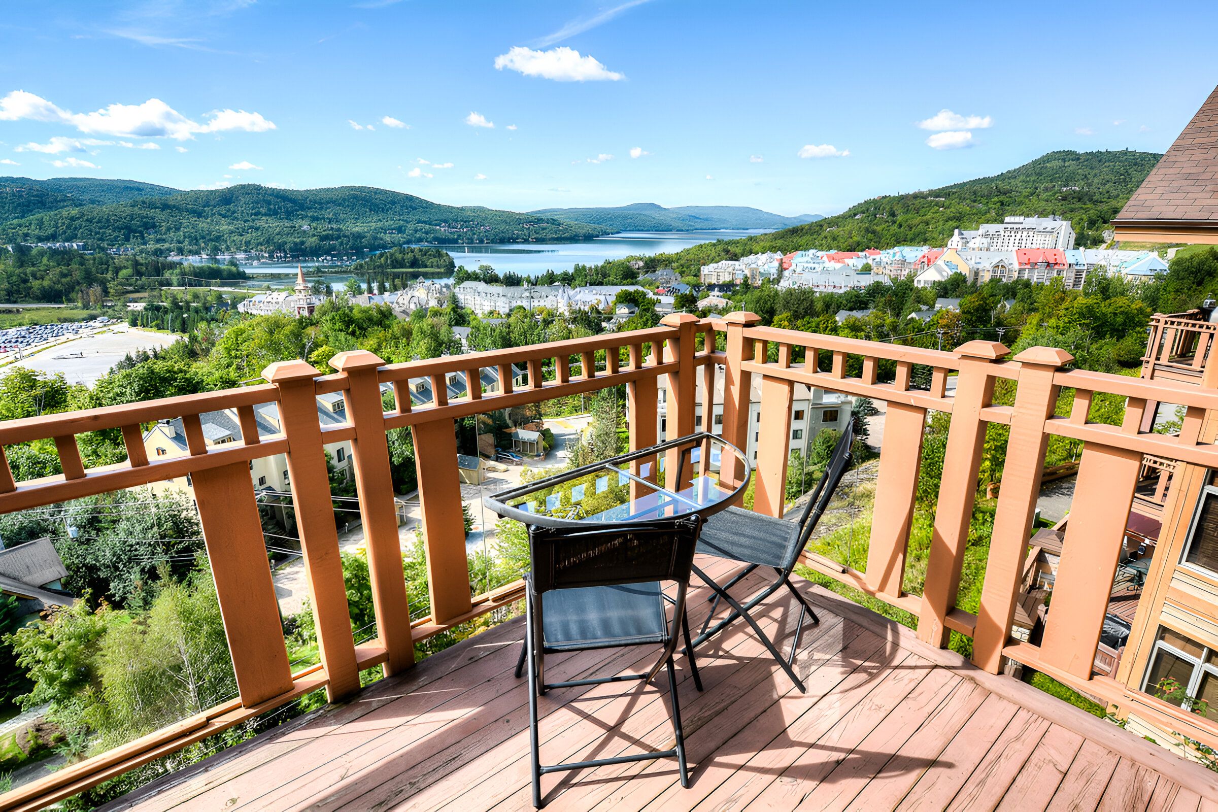 Ein Balkon mit Glastisch und Stuhl mit Blick auf eine Stadt und Hügel.