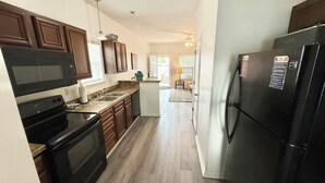 A modern kitchen with dark wooden cabinets, a black refrigerator, and a microwave.