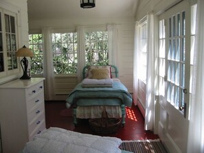 A room with a bed, a dresser, and a window with curtains.