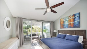A bedroom with a large bed, a ceiling fan, a sliding glass door leading to a balcony, and a painting on the wall. - World Famous Seven Mile Beach "Location, Cayman Islands" Welcome to Paradise. (George Town)