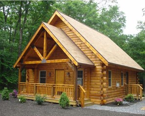 A log cabin with a prominent gable roof, a front porch with railings, and a small front yard with shrubs. - Spruce Run Hideaway, Log Cabin Alone On 245 Acres Of Forest, Lewisburg Pa (Lewisburg)