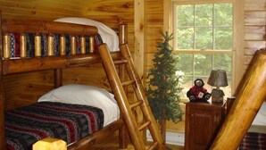 Ein Zimmer in einer Holzhütte mit einem Etagenbett, einer Himmelsleiter, einer kleinen Schrank und einem Weihnachtsbaum.