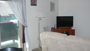 A bedroom with a bed, a TV, a dresser, and a window with a curtain.