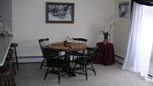 A dining area with a round table, four chairs, a vase with flowers, and artwork on the walls.