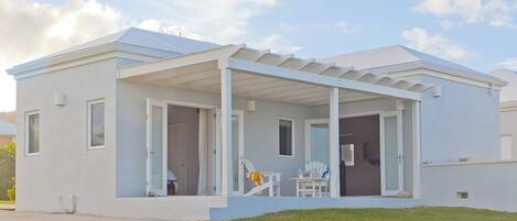 A modern single-story house with a covered porch, large windows, and a well-maintained lawn.