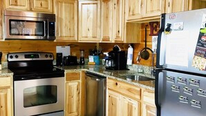 A kitchen with wooden cabinets, stainless steel appliances, and a refrigerator with magnets. - Private Hideaway near Pigeon Forge; Convenient to Attractions; Five-Star Reviews (Sevierville)