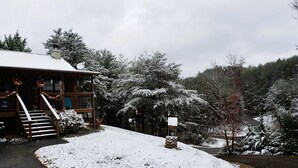 A lodge with a wooden exterior, a covered porch, and a snow-covered yard. - Private Hideaway near Pigeon Forge; Convenient to Attractions; Five-Star Reviews (Sevierville)