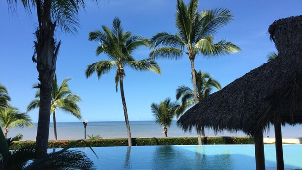 A poolside view with palm trees and a beach in the background. - Beachfront Panoramic Oceanview Modern Luxury (Old Town Romantic Zone) (Puerto Vallarta)