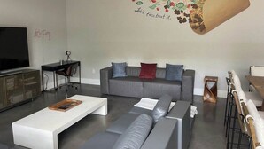 Ein modernes Wohnzimmer mit einem grauen Sofa, einem weißen Couchtisch und einem Fernseher.