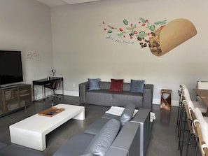 Ein modernes Wohnzimmer mit einem grauen Sofa, einem weißen Couchtisch und einem Fernseher.