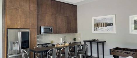 A modern kitchen with a central island, stainless steel appliances, and a ceiling fan.