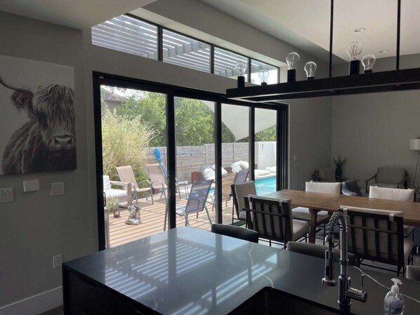 A modern kitchen with a large window overlooking a pool area. - Modern 5BR Oasis | 2-Home w/ Pool & Hot Tub (Austin)
