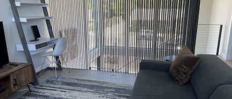 Una sala moderna con un sofá gris, un aparador de madera, una silla blanca y una alfombra a rayas.