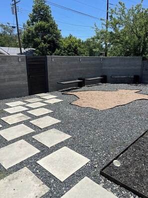 An outdoor area with a paved walkway, a concrete wall, and a seating area with benches.