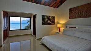 Une chambre avec une grande fenêtre, un lit, une table de chevet et une œuvre d’art accrochée au mur.