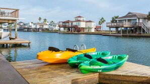 A wooden dock with kayaks and a view of waterfront houses. - Waterfront luxury! Free bikes & kayaks! Great fishing! Bike to the beach! (Galveston)