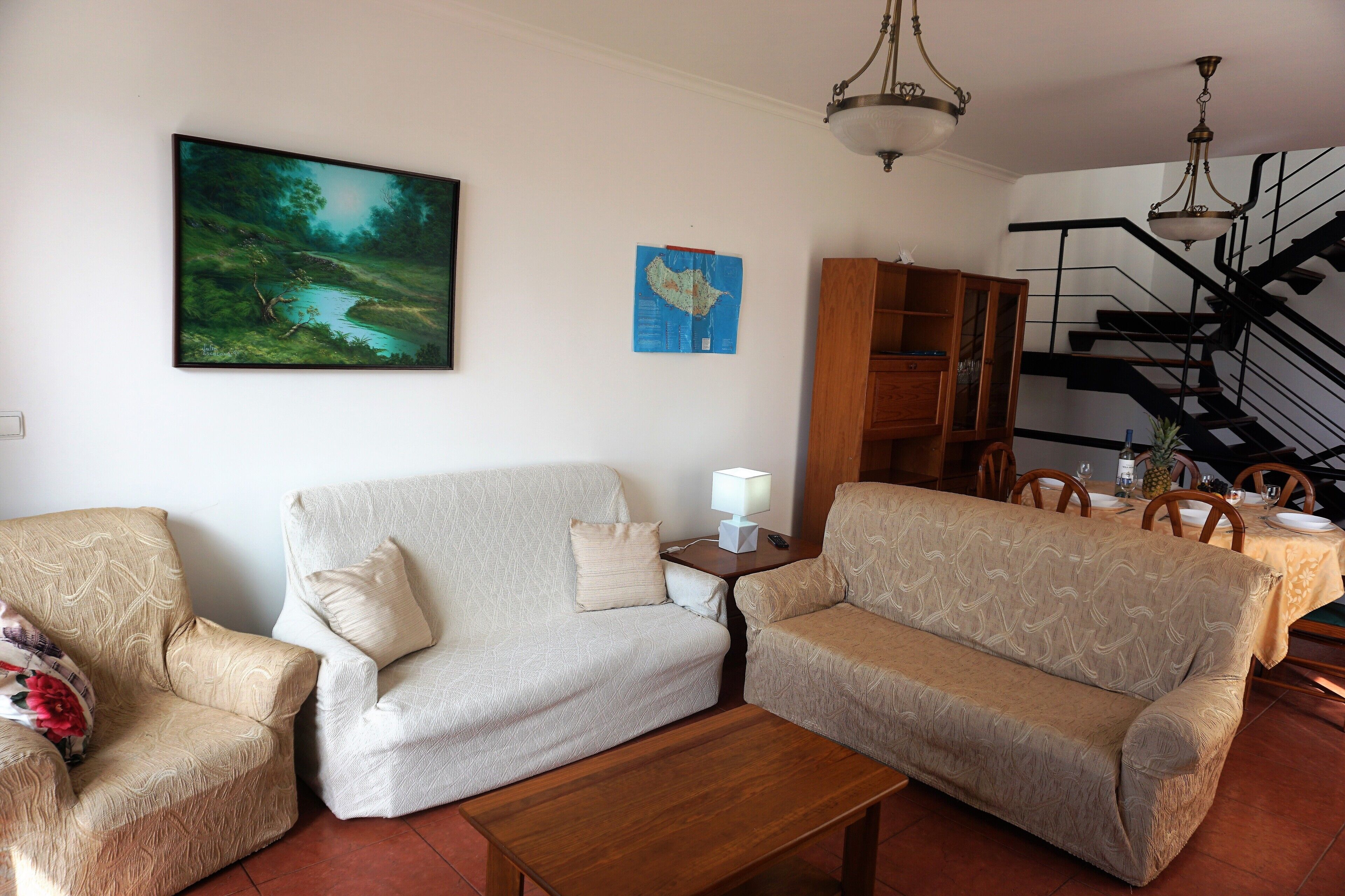 A living room with two sofas, a coffee table, a map on the wall, and a staircase.