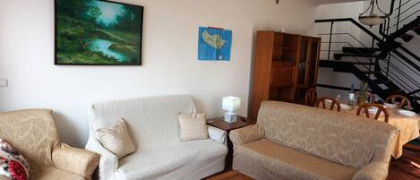A living room with two sofas, a coffee table, a map on the wall, and a staircase.