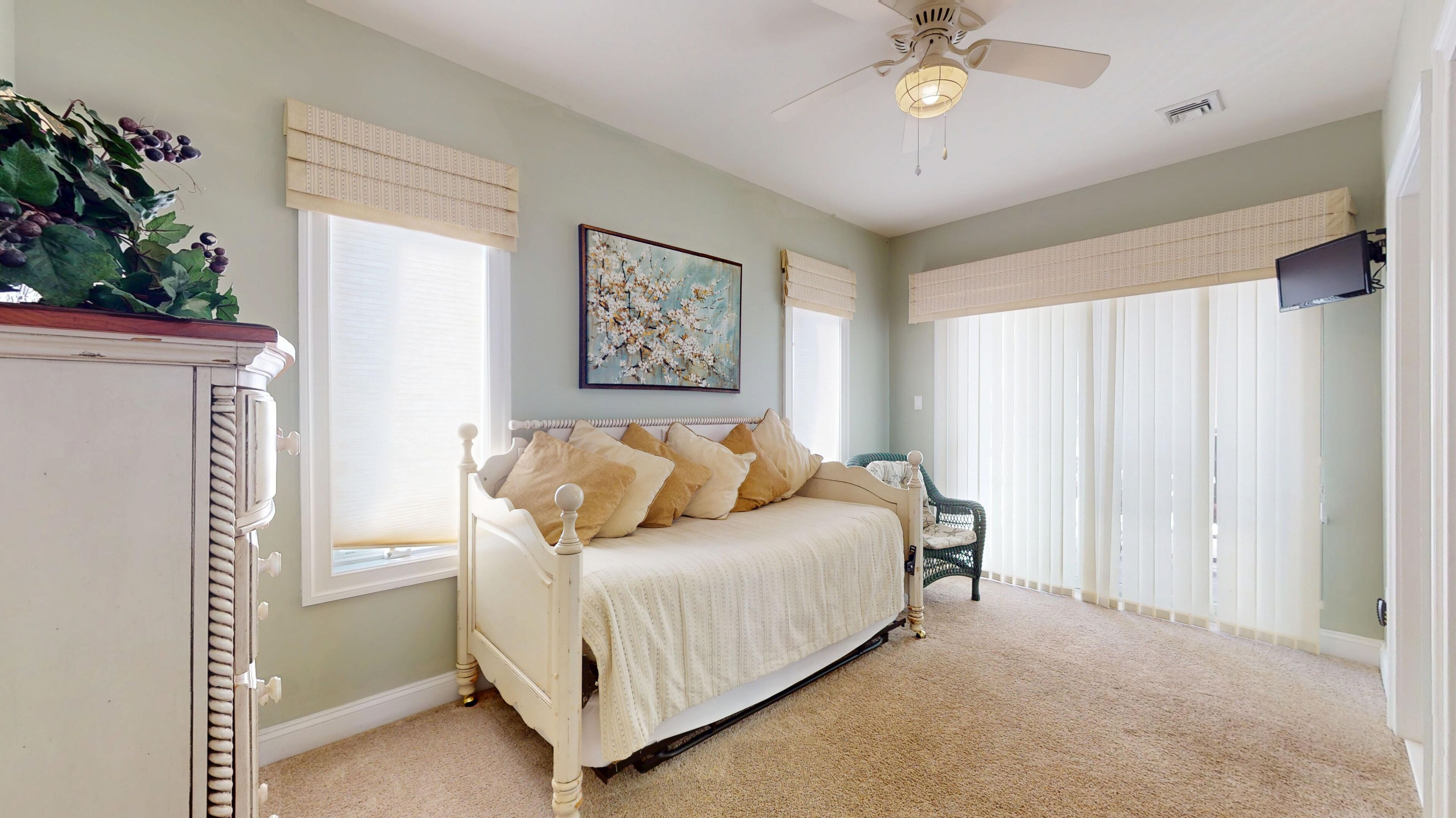 A bedroom with a bed, a ceiling fan, a window with blinds, and a painting on the wall.