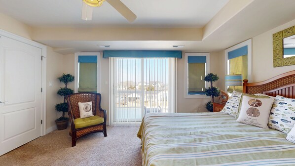 A bedroom with a bed, a chair, a window with blinds, and a ceiling fan.