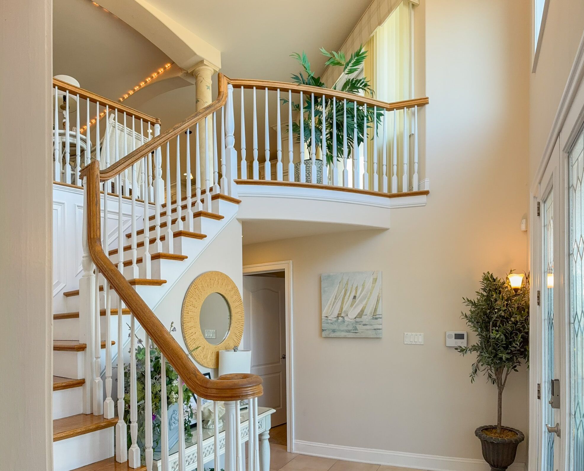 A multi-level staircase with white railings and wooden steps, a round mirror, and a potted plant on the landing.