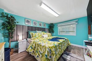 A bedroom with a bed, nightstand, dresser, and a potted plant. - Heaven Can't Wait:  ON the BEACH!! Heated pool + hot tub, private dock. 7BR/5BA (Stuart)