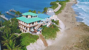 A beachfront property with a large building featuring multiple balconies, a dock, and a view of the ocean. - Heaven Can't Wait:  ON the BEACH!! Heated pool + hot tub, private dock. 7BR/5BA (Stuart)