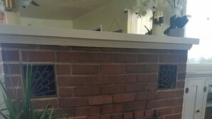 A brick fireplace with a red chest in front, a potted plant, and a white cabinet with a decorative screen. - Three Bedrooms Two Baths sleeps 6 - Walking distance to Downtown Paso Robles (Paso Robles)