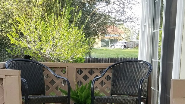 A wooden deck with two black wicker chairs and a potted plant. - Three Bedrooms Two Baths sleeps 6 - Walking distance to Downtown Paso Robles (Paso Robles)