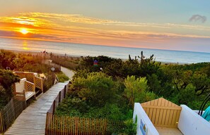 A wooden boardwalk leading to a beach with a sunset in the background. - Escape to The Ocean! , Ocean Front, Beautiful View, Pool! (Ocean City)