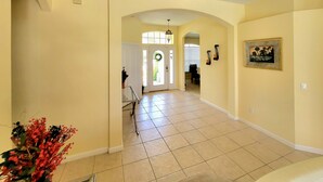 A spacious hallway with a tiled floor, a decorative archway, and a door with a wreath. - Immaculate Spacious Villa.No rear neighbors,Games Room,office,Large pool,hot spa (Davenport)