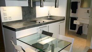 Een moderne keuken met een glazen eettafel, witte stoelen en een inbouwoven.