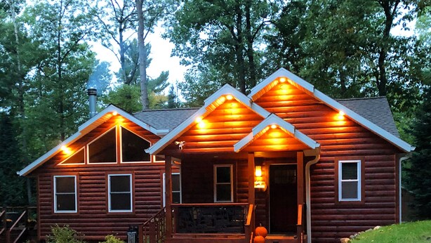 A log cabin with a porch and a covered entryway, surrounded by a gravel driveway and a stone wall. - Cozy Cabin Secluded in the Woods.  Wildlife Abundant.  Not a neighbor in sight! (Harshaw)