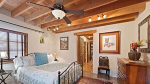A bedroom with a bed, a nightstand, a dresser, a chair, and a ceiling fan.