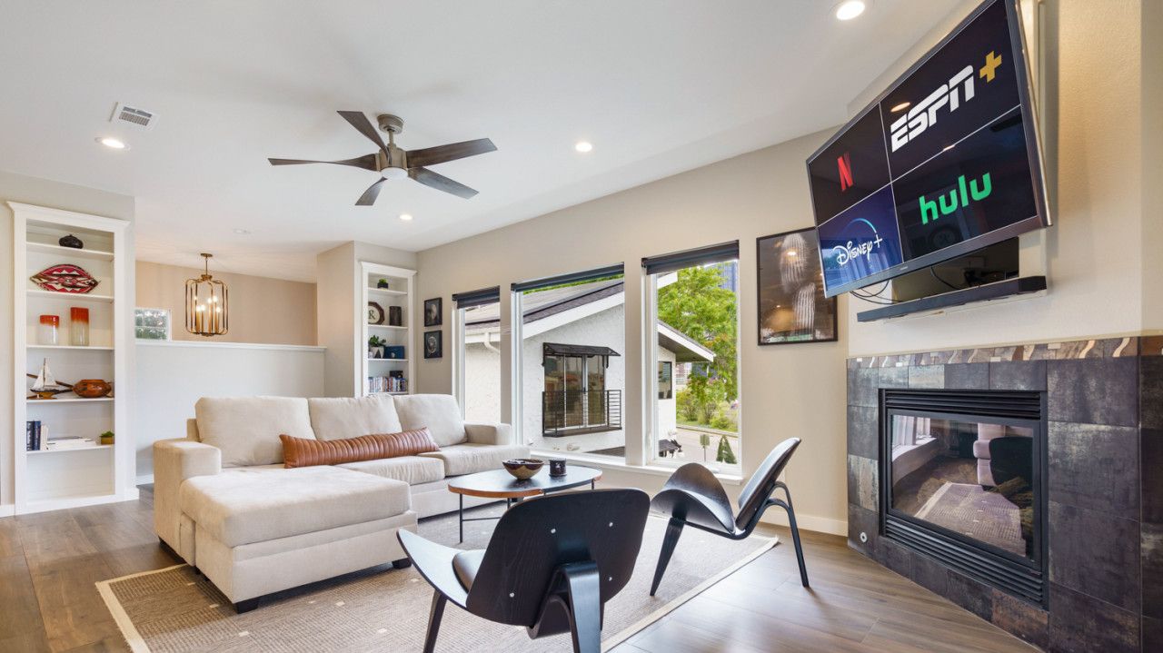 A modern living room with a sofa, chairs, a fireplace, and a mounted TV displaying streaming services.