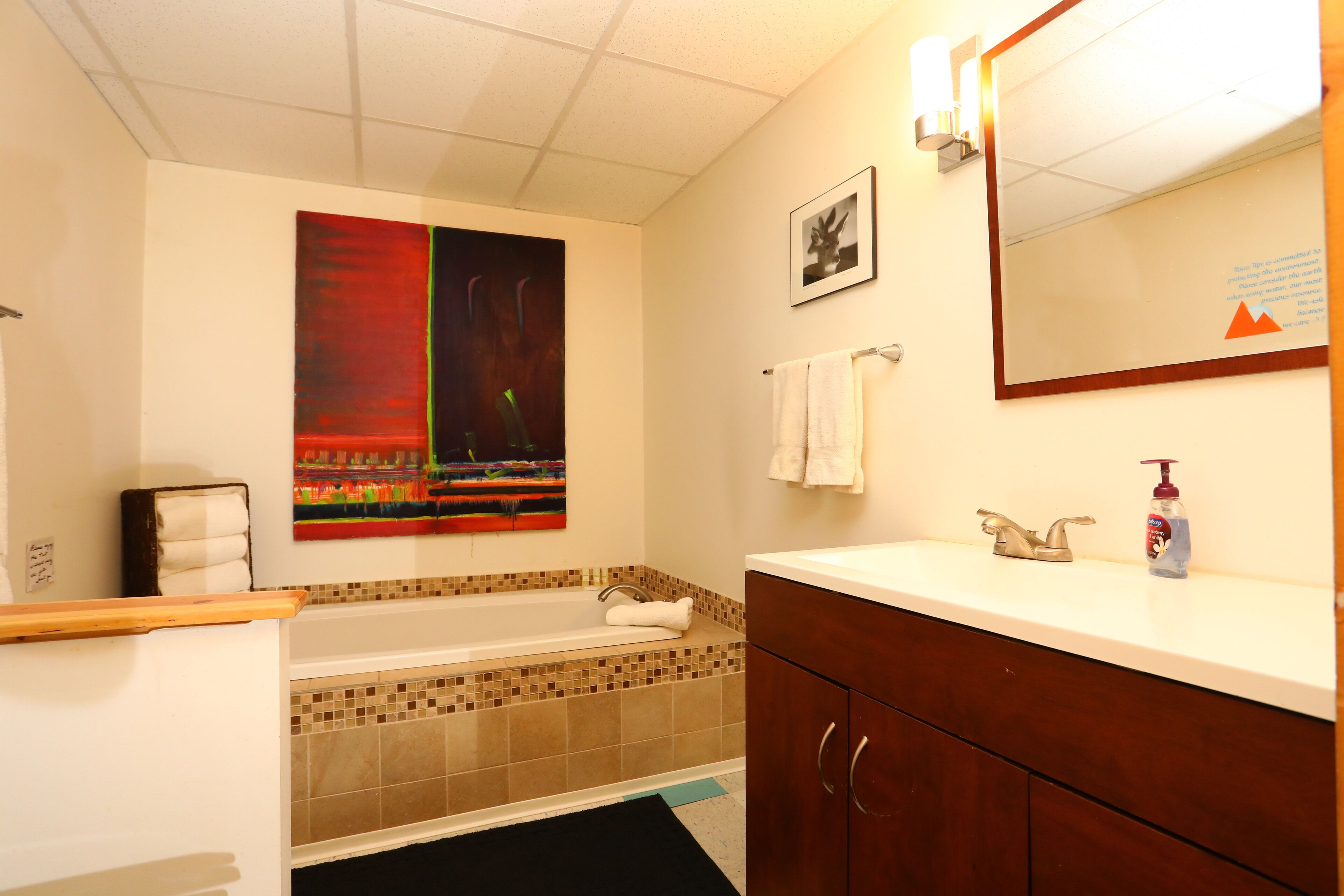 Ein Badezimmer mit Badewanne, Waschbecken, Spiegel und einem Bild an der Wand.