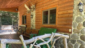 A wooden cabin with a porch, stone wall, and a carved elk head decoration. - Lakefront on 31 acres, Kayaks, boat, Hiking, Fishing, Private Lake. (Paupack)