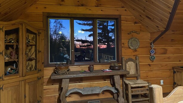 A wooden cabin interior with a large window, wooden furniture, and a rustic decor. - Lakefront on 31 acres, Kayaks, boat, Hiking, Fishing, Private Lake. (Paupack)