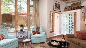 A cozy living room with a light blue sofa, a wooden bench, and a coffee table with a tray of snacks and drinks.
