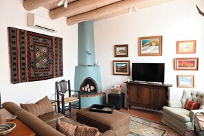 A living room with a sofa, a television, a fireplace, and several framed pictures on the wall. - South Capitol Historic Area!
1 Mile from the Plaza!
2 King BR, 2 BA, 2 Patios! (Santa Fe)