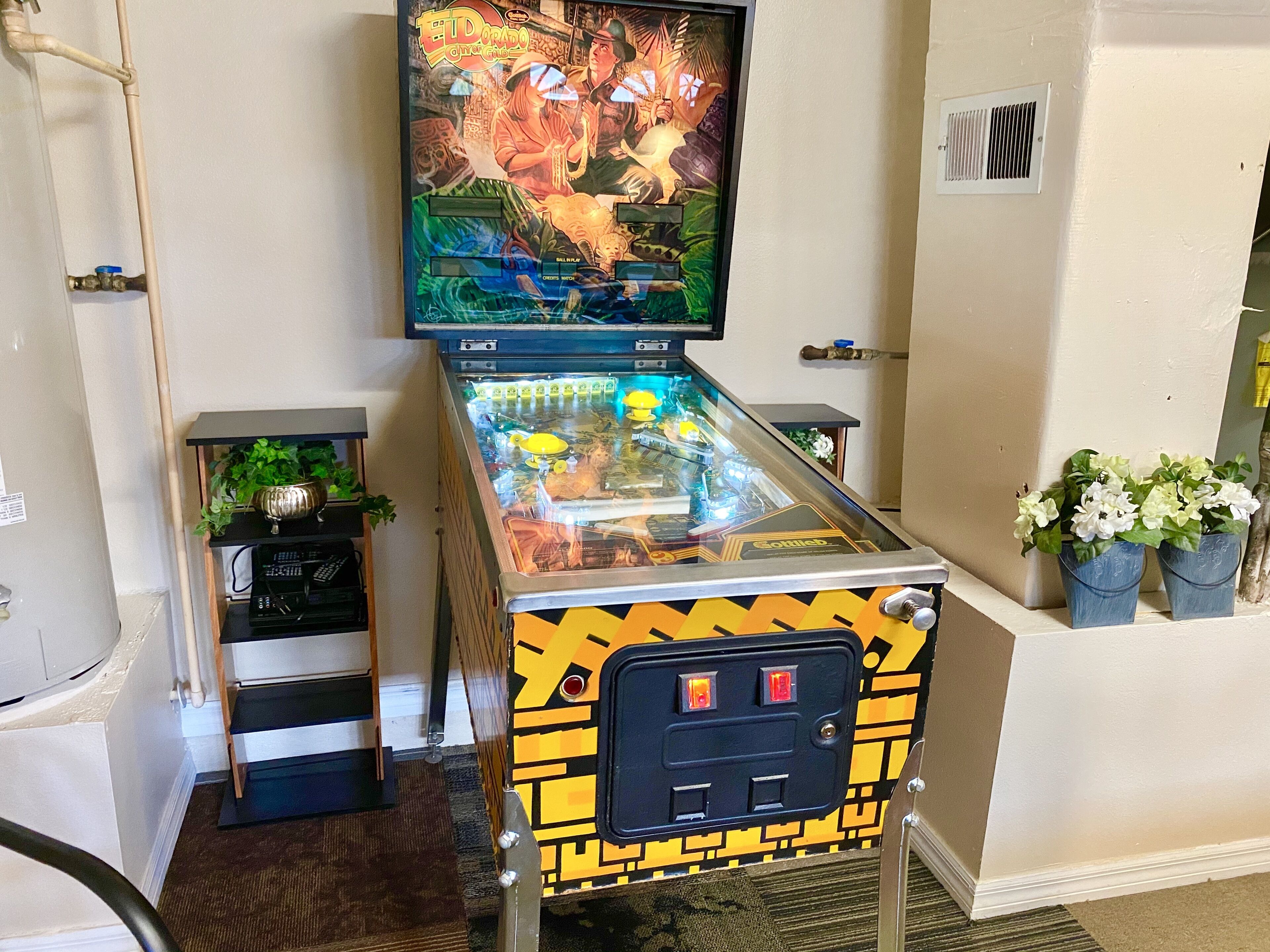 Un flipper doté d’un plateau de jeu coloré et d’un téléviseur fixé au-dessus.