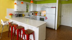 A kitchen with white cabinets, a central island with stools, a microwave, and a refrigerator. - Lakefront 🛶 • Spa ♨️ • Firepit 🔥 • Boating 🚣‍♂️ • Game Rm 🎮 • Fishing 🎣 • Sunsets 🌅 (Poconos Lake)