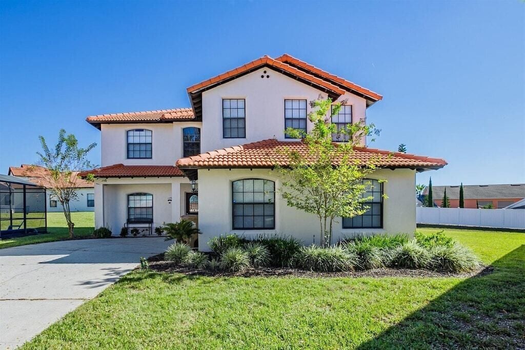 A two-story house with a red-tiled roof, a small front porch, and a well-maintained lawn.