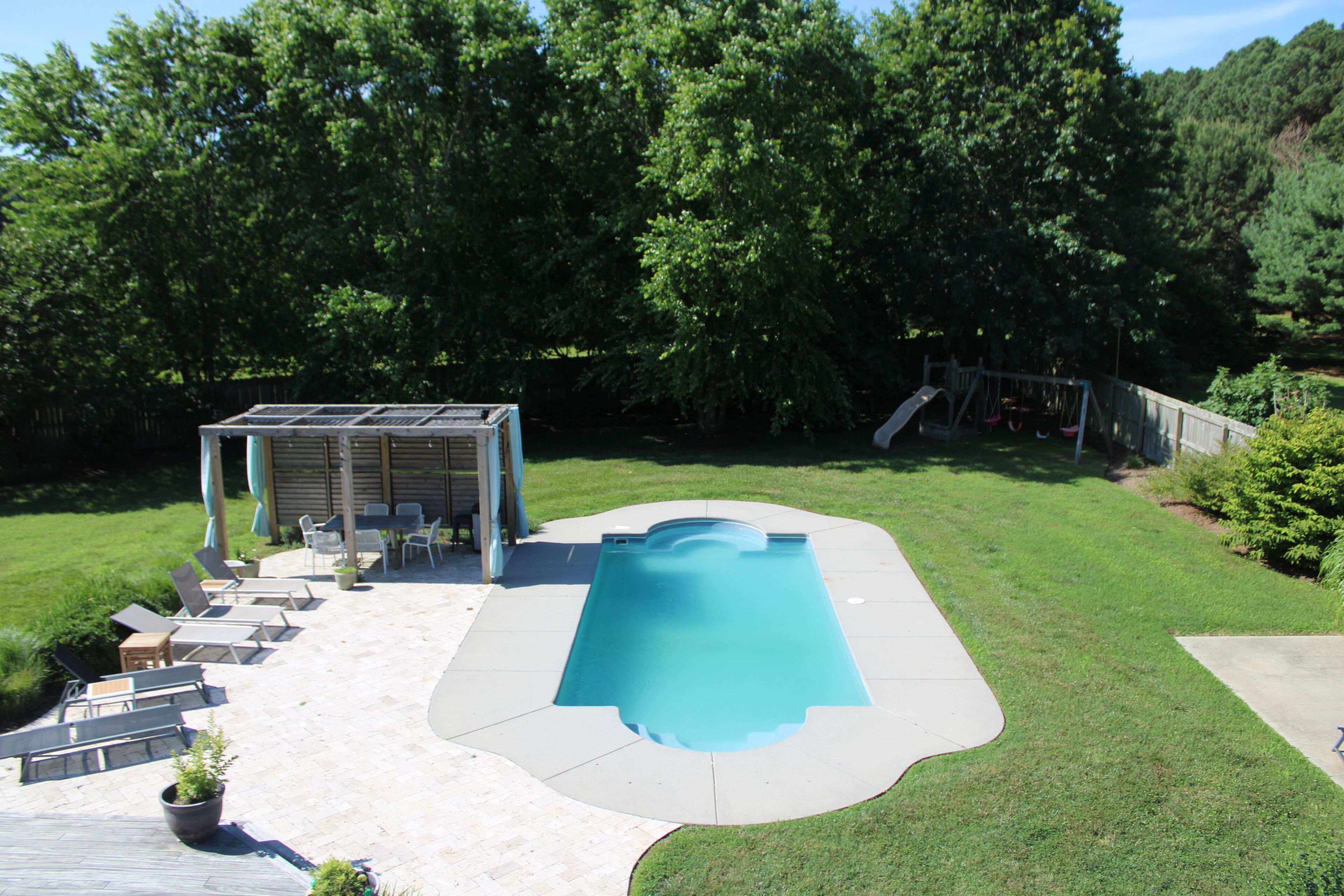 Um quintal com piscina, varanda coberta e escorrega.