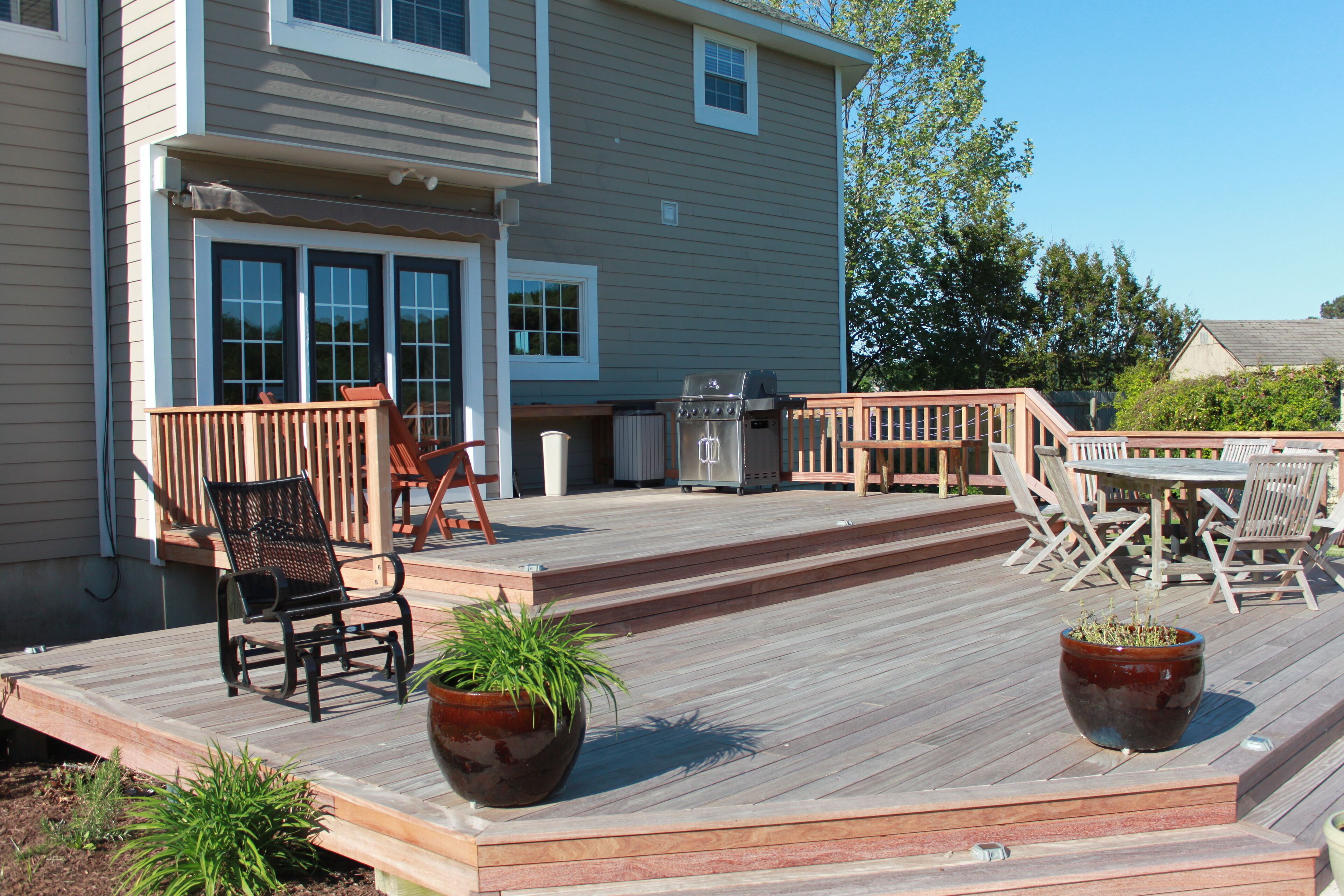 A wooden deck with outdoor furniture, including chairs and a table, and potted plants.