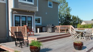 A wooden deck with outdoor furniture, including chairs and a table, and potted plants. - Family vacation retreat w/ In-ground Pool with private Chesapeake Bay access! (Cape Charles)